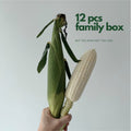 Hand holding one fresh jagung putih cob showing size